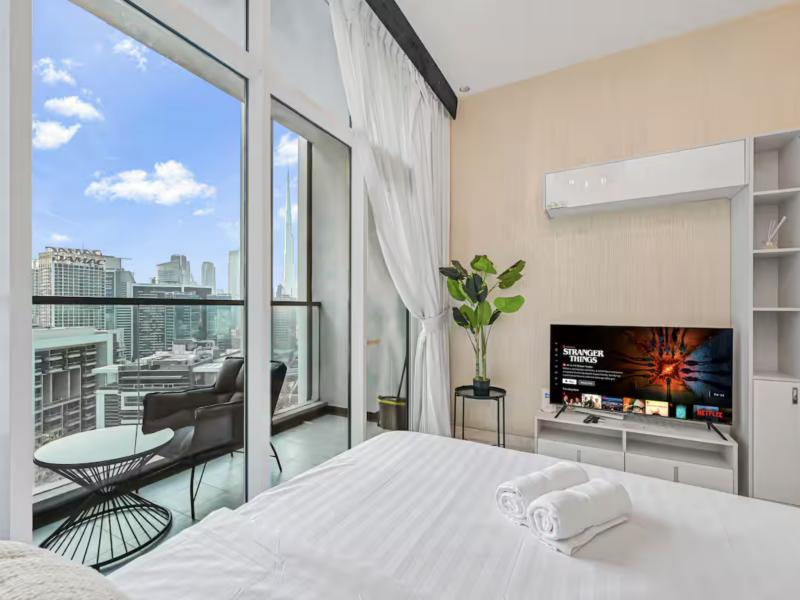 Bed facing floor-to-ceiling windows and a smart TV